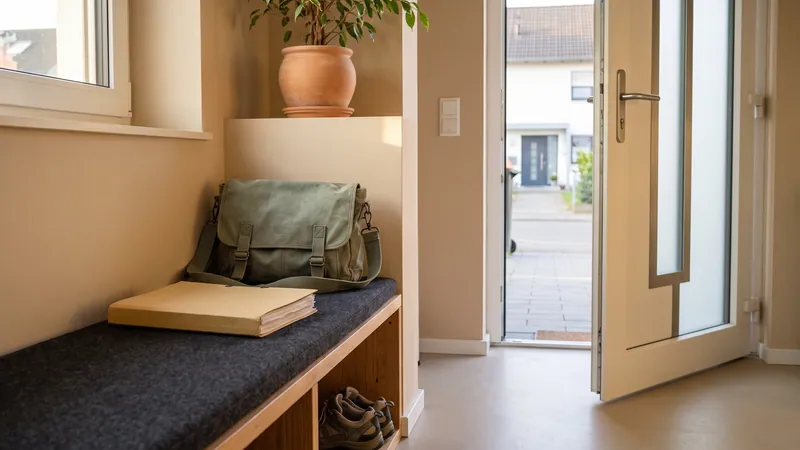 Gepackte Tasche und Mappe auf einer Bank an der Wohnungstür.